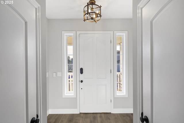 foyer with plenty of natural light, dark hardwood / wood-style floors, and a notable chandelier