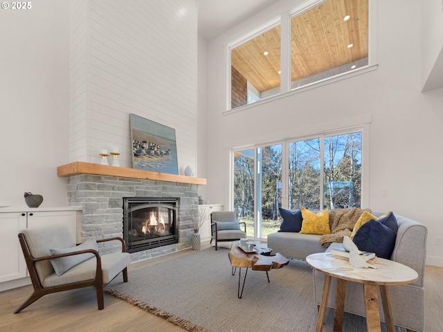 living room featuring light wood-type flooring, a fireplace, and a high ceiling