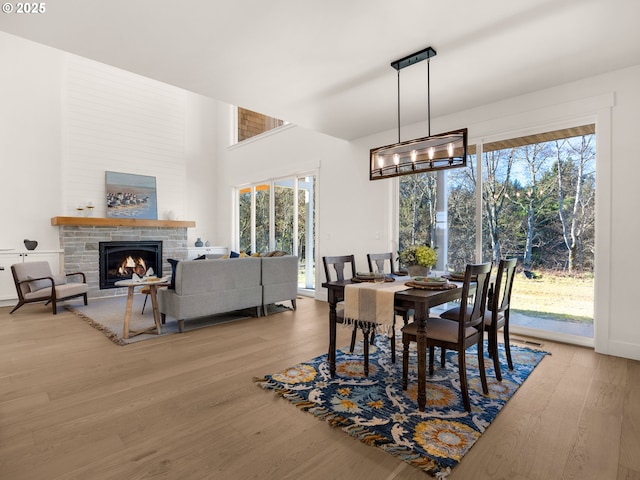 dining space with a stone fireplace, an inviting chandelier, and light hardwood / wood-style floors