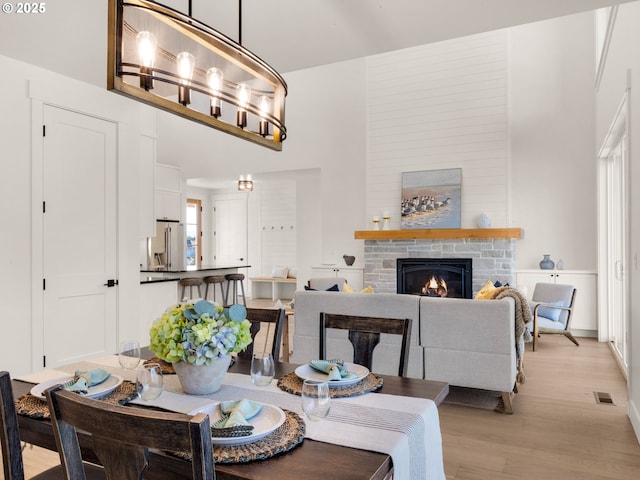 dining area with a notable chandelier, a stone fireplace, and light hardwood / wood-style flooring