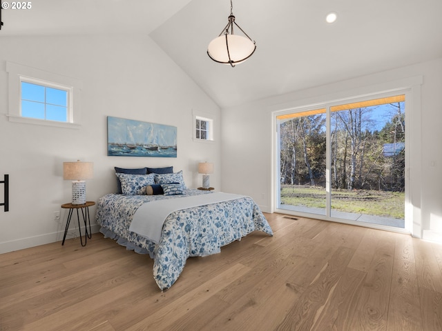 bedroom with high vaulted ceiling, light hardwood / wood-style floors, and multiple windows