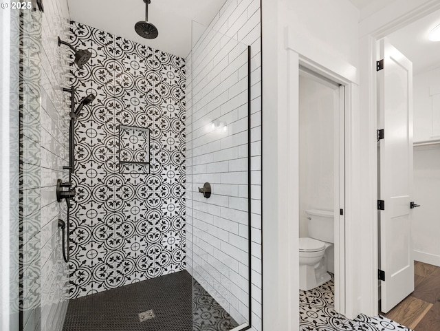 bathroom featuring hardwood / wood-style floors, a tile shower, and toilet