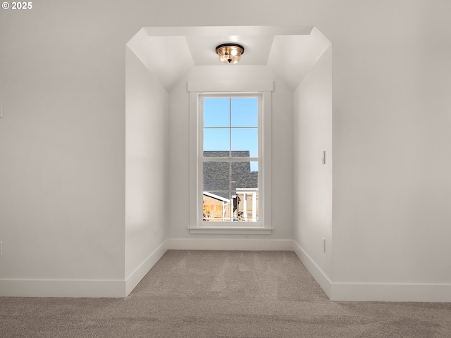 spare room featuring vaulted ceiling and carpet flooring