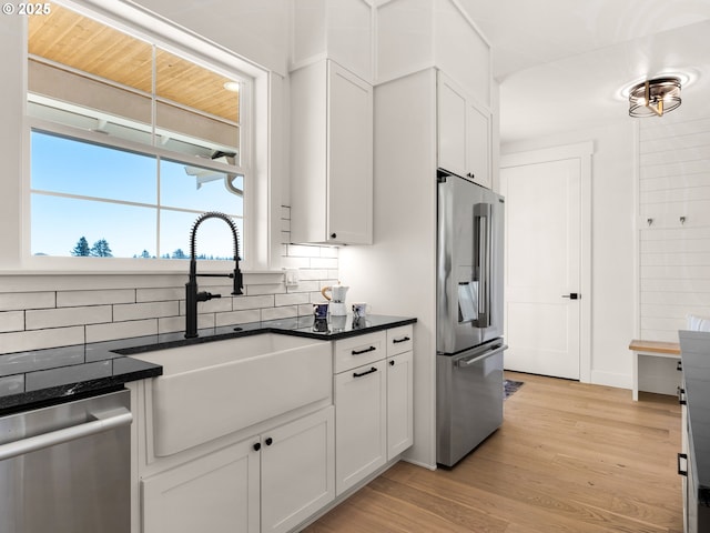 kitchen with sink, white cabinetry, tasteful backsplash, light hardwood / wood-style flooring, and stainless steel appliances