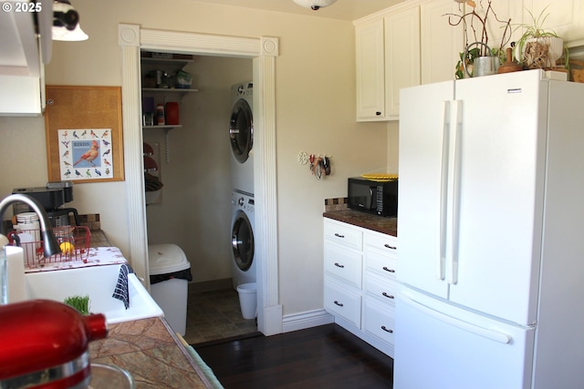 1407 9th St, Baker City, OR 97814 - kitchen featuring freestanding refrigerator, stacked washer / dryer, black microwave, a sink, and white cabinetry