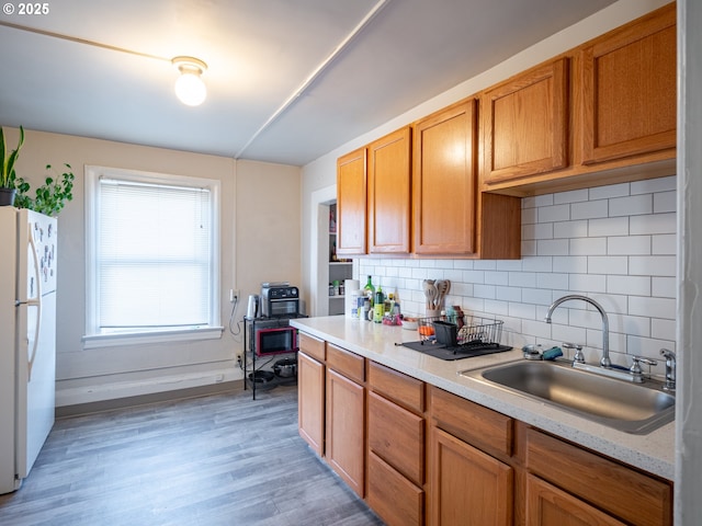 kitchen with sink, backsplash, hardwood / wood-style floors, and white fridge