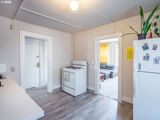 2312 SE Madison St, Portland, OR 97214 - kitchen with white appliances, light wood finished floors, light countertops, and baseboards