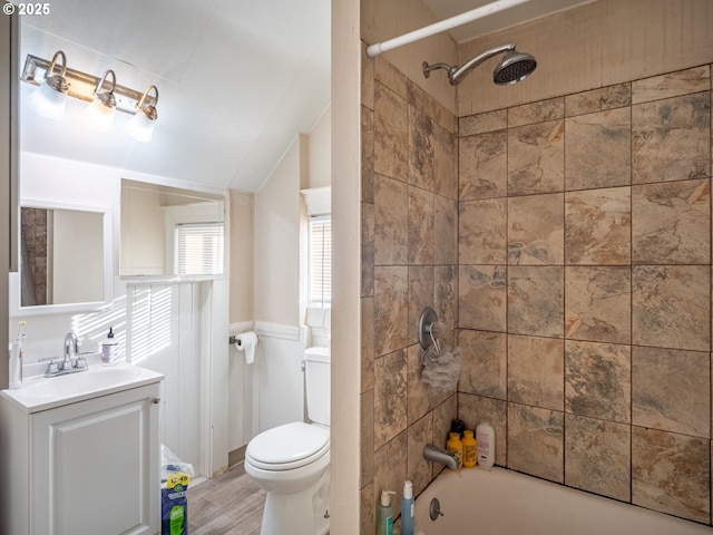 full bathroom with tiled shower / bath, wood-type flooring, lofted ceiling, vanity, and toilet