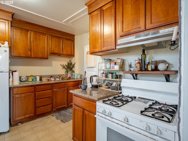 2312 SE Madison St, Portland, OR 97214 - kitchen with white appliances, under cabinet range hood, brown cabinets, light stone countertops, and a sink