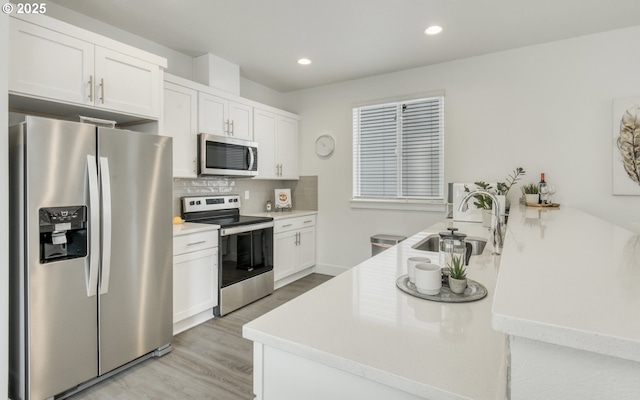 3037 SW Sherman Pl, Beaverton, OR 97003 - kitchen with stainless steel appliances, a sink, decorative backsplash, light wood finished floors, and white cabinetry