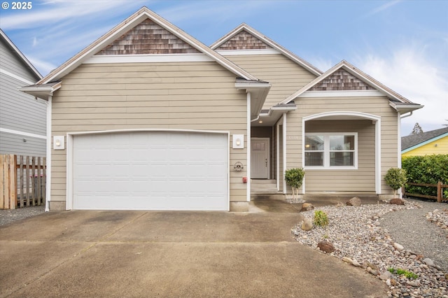 view of front of home featuring driveway, an attached garage, and fence