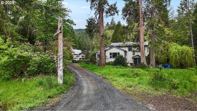 view of front of house with driveway and a forest view