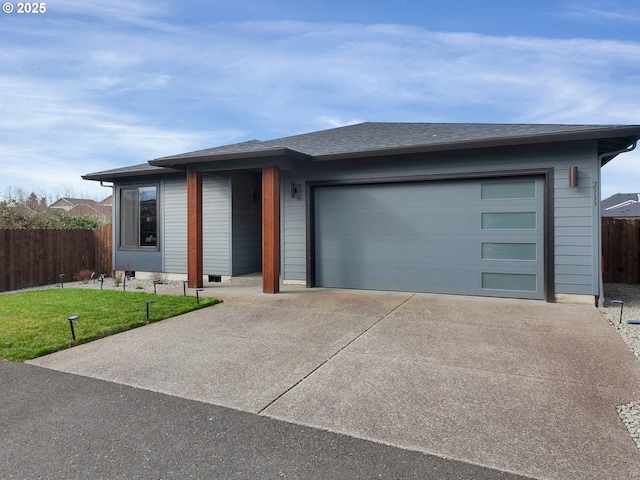 view of front of house with a front lawn, concrete driveway, a garage, and fence