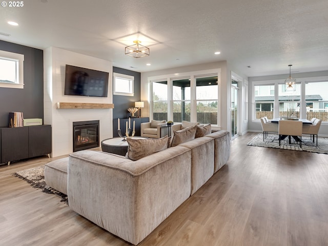 living area featuring a wealth of natural light, light wood-style flooring, and a fireplace