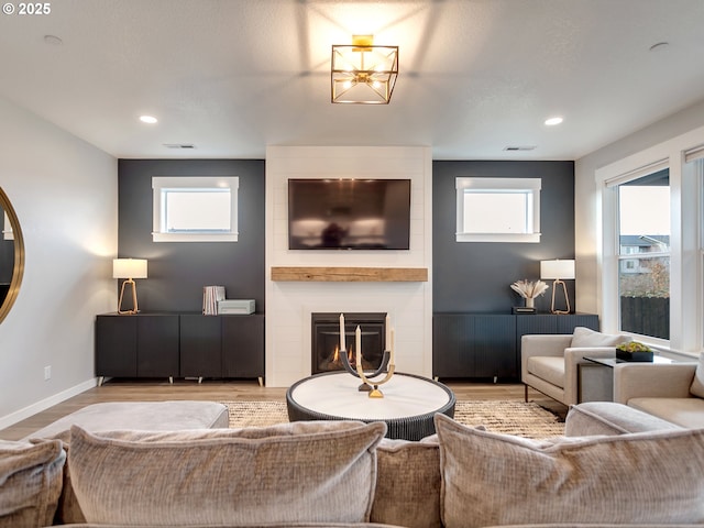 living room with visible vents, baseboards, recessed lighting, a fireplace, and wood finished floors