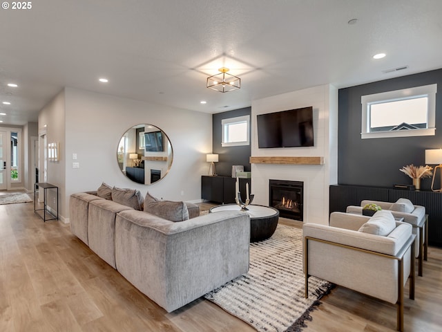 living room featuring recessed lighting, light wood-style flooring, a large fireplace, and baseboards