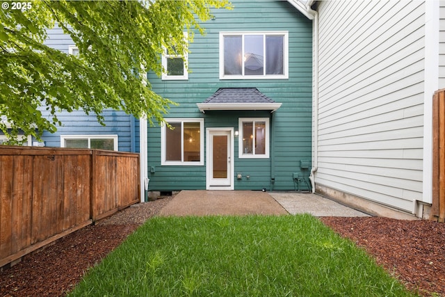 rear view of property featuring a lawn, a shingled roof, a patio, and fence