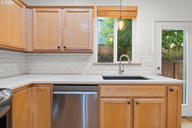 kitchen with light stone counters, stainless steel dishwasher, decorative backsplash, and a sink