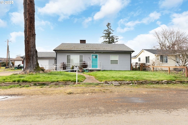 ranch-style house featuring roof with shingles, fence, a chimney, and a front lawn