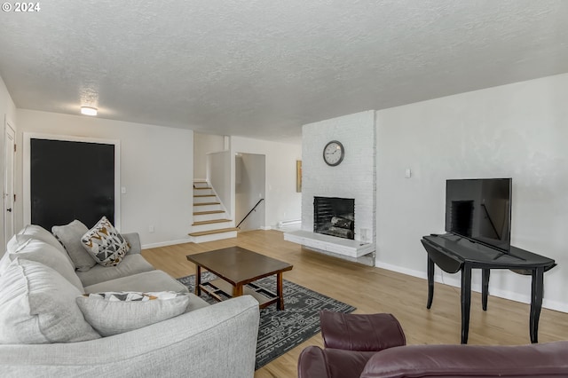 living room with hardwood / wood-style flooring, a fireplace, and a textured ceiling