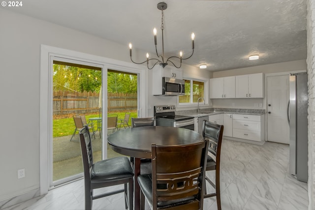 dining space with an inviting chandelier, plenty of natural light, and sink