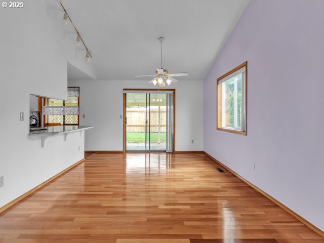 interior space with vaulted ceiling, light wood-type flooring, ceiling fan, and a healthy amount of sunlight