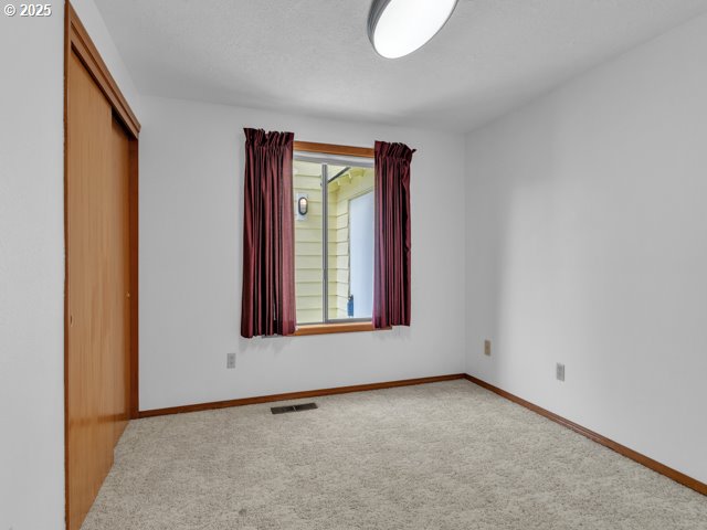 unfurnished bedroom featuring carpet flooring, a closet, baseboards, and visible vents