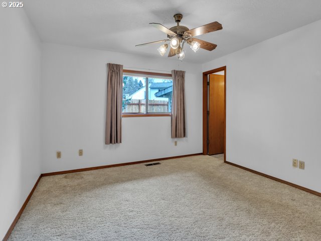 carpeted empty room featuring a ceiling fan, baseboards, and visible vents