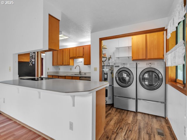 laundry room with wood finished floors, cabinet space, separate washer and dryer, and visible vents