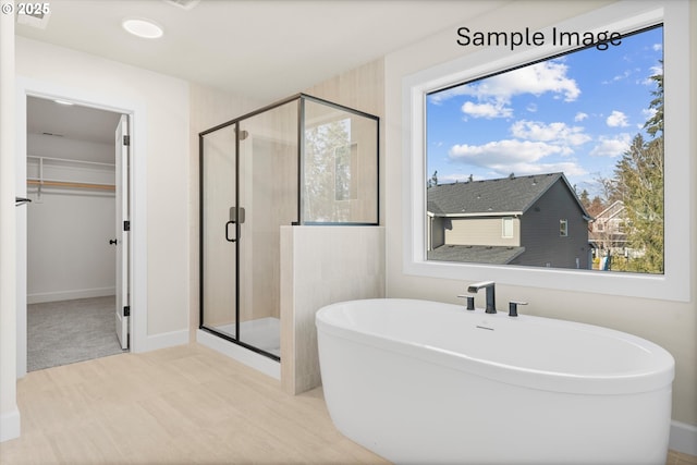 bathroom with a stall shower, a freestanding tub, and a walk in closet