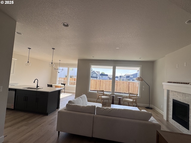 844 NE 17th Ave, Canby, OR 97013 - living area featuring wood finished floors, a textured ceiling, a brick fireplace, baseboards, and recessed lighting