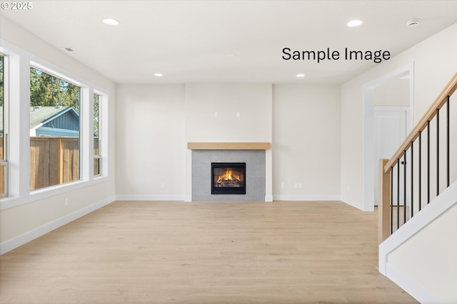 unfurnished living room with light wood finished floors, recessed lighting, a fireplace, stairs, and baseboards