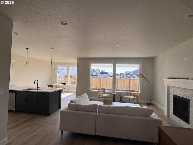844 NE 17th Ave, Canby, OR 97013 - living room with wood finished floors, a textured ceiling, a brick fireplace, baseboards, and recessed lighting