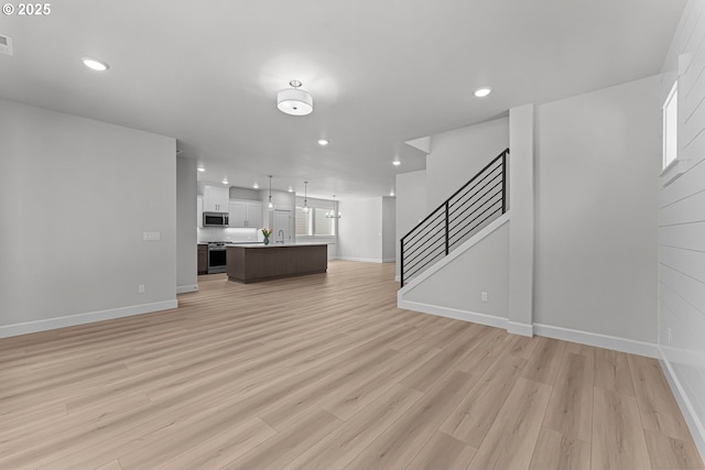 16401 SW Cambridge Ln, Durham, OR 97224 - unfurnished living room with baseboards, recessed lighting, light wood-type flooring, and stairs
