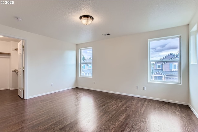 20372 SW Verona Ct, Beaverton, OR 97003 - unfurnished bedroom with dark wood-type flooring, a textured ceiling, and a walk in closet