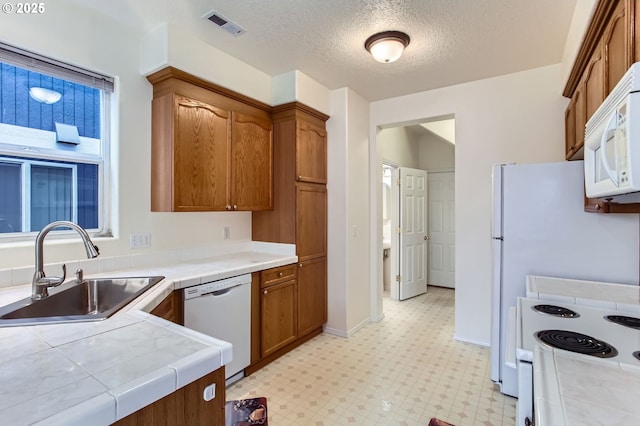 20372 SW Verona Ct, Beaverton, OR 97003 - kitchen featuring white appliances, tile countertops, brown cabinets, light flooring, and a textured ceiling