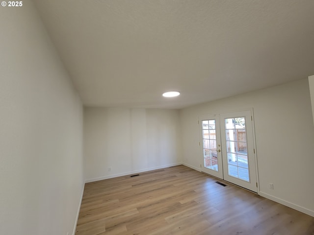 spare room with french doors and light hardwood / wood-style floors