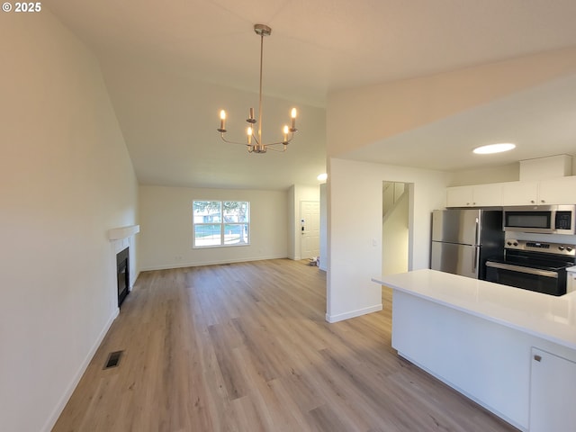 kitchen featuring a chandelier, hanging light fixtures, light wood-type flooring, appliances with stainless steel finishes, and white cabinets