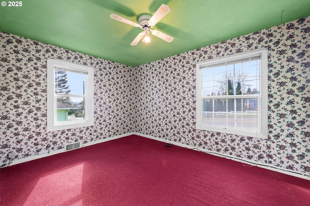 carpeted spare room with a ceiling fan, visible vents, baseboards, and wallpapered walls