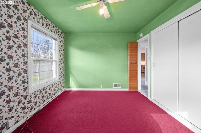 unfurnished bedroom featuring wallpapered walls, visible vents, baseboards, ceiling fan, and carpet floors