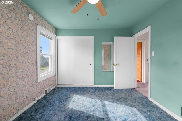 unfurnished bedroom featuring a closet, carpet flooring, ceiling fan, and visible vents