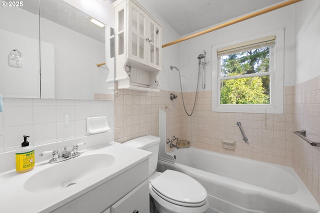 full bathroom with tile walls, toilet, wainscoting, vanity, and  shower combination