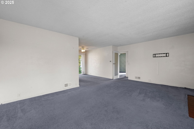 spare room with visible vents, dark carpet, and a textured ceiling