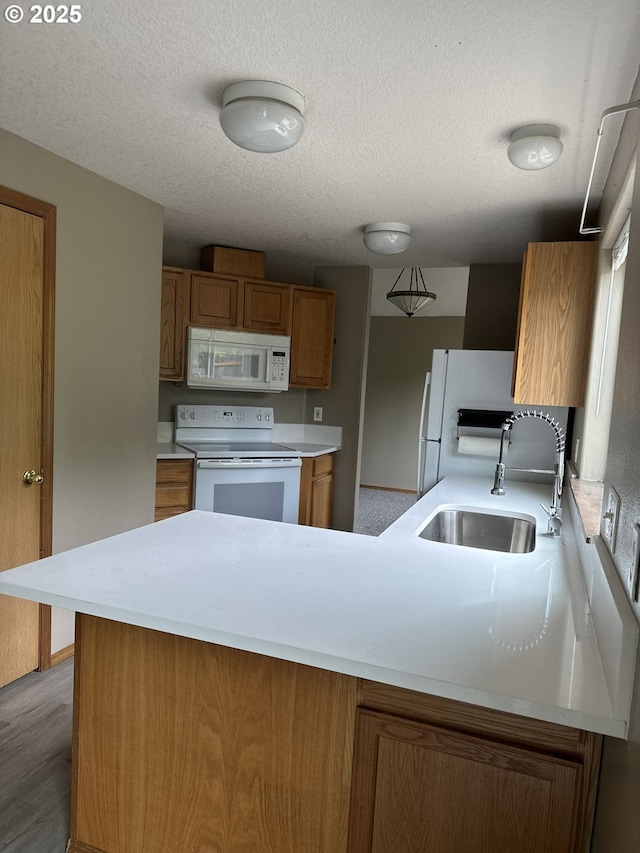14237 SE Lee Ave, Milwaukie, OR 97267 - kitchen featuring white appliances, a sink, brown cabinetry, a peninsula, and light countertops