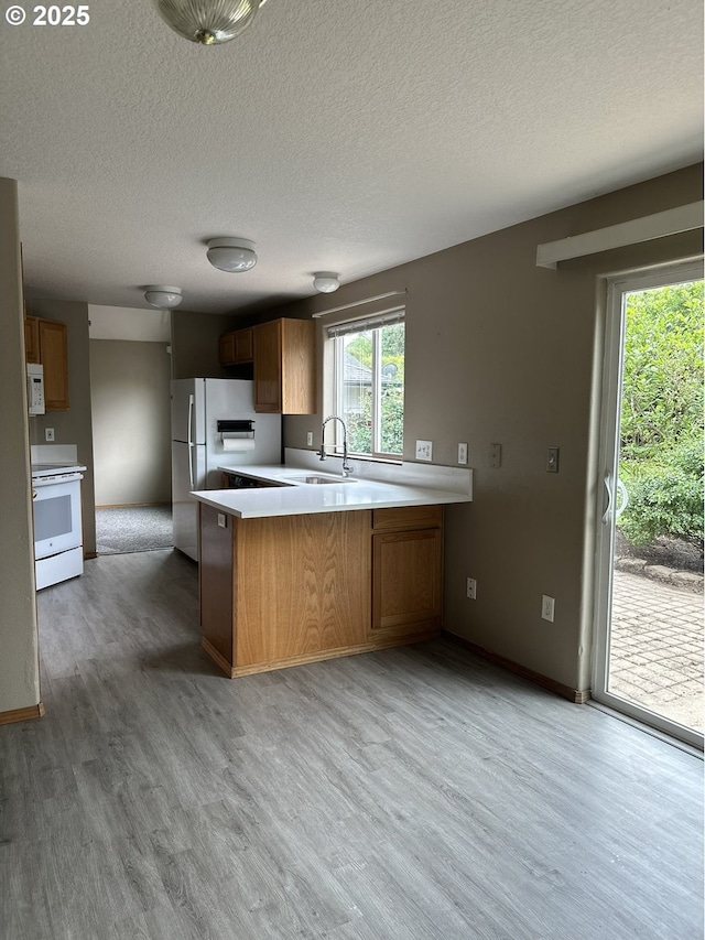 14237 SE Lee Ave, Milwaukie, OR 97267 - kitchen with white appliances, a peninsula, light wood-type flooring, light countertops, and a textured ceiling