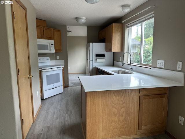 14237 SE Lee Ave, Milwaukie, OR 97267 - kitchen featuring white appliances, a sink, a peninsula, light countertops, and light wood-type flooring