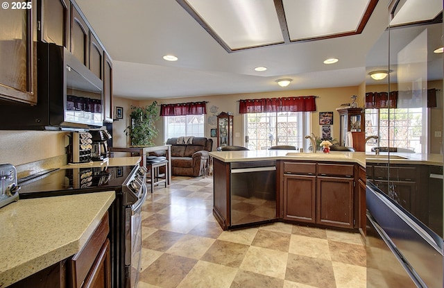 kitchen with decorative light fixtures, sink, stainless steel appliances, and dark brown cabinets