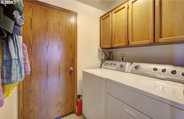 clothes washing area featuring washing machine and clothes dryer and cabinets