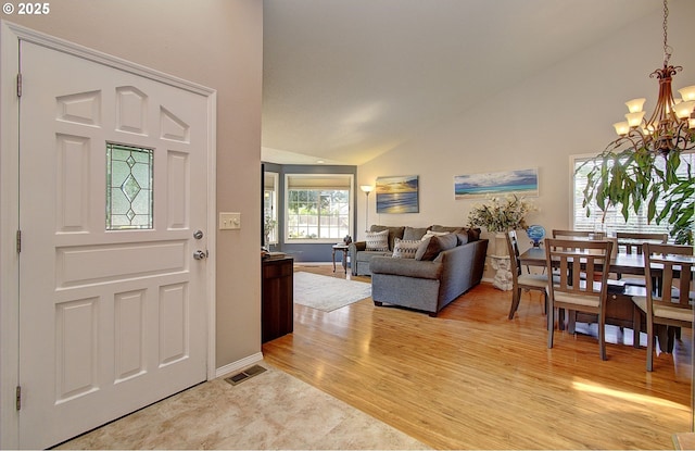 entryway with high vaulted ceiling, light wood-type flooring, and a notable chandelier