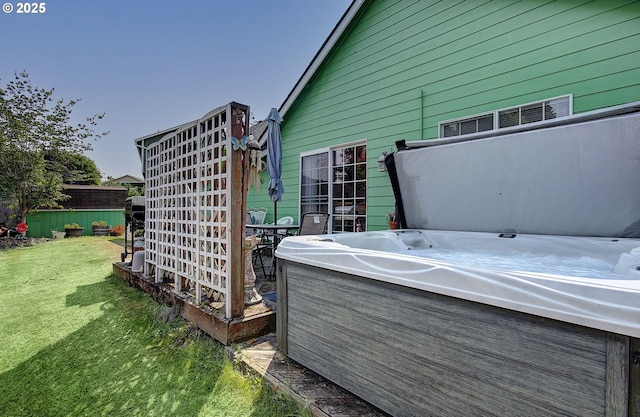 deck with a hot tub and a lawn